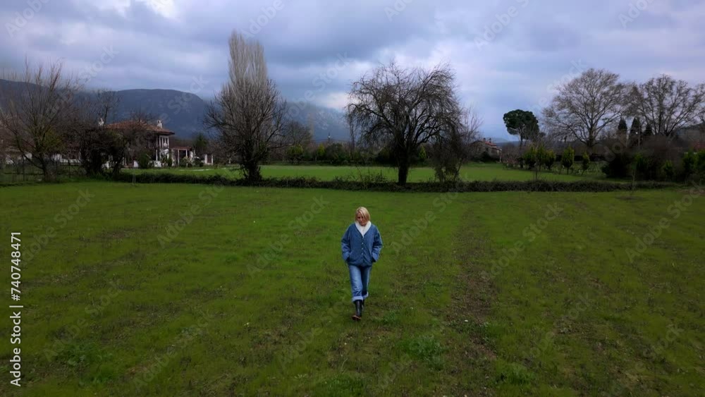 Tracking shot of a woman walking in the green fields Tracking shot of a woman walking in the green fields