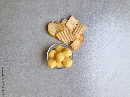 Hand holding Crispy corrugated potato chips or potato chips and Cheese Corn balls. Junk food. Close up. Keripik Singkong or Keripik Kentang dan snack bulat photo