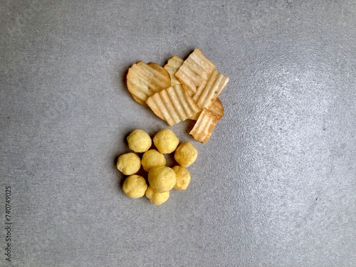 Hand holding Crispy corrugated potato chips or potato chips and Cheese Corn balls. Junk food. Close up. Keripik Singkong or Keripik Kentang dan snack bulat photo