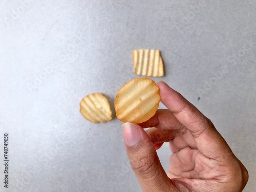 Hand holding Crispy corrugated potato chips or potato chips background. Junk food. Close up photo