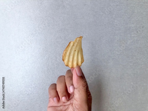 Hand holding Crispy corrugated potato chips or potato chips background. Junk food. Close up photo