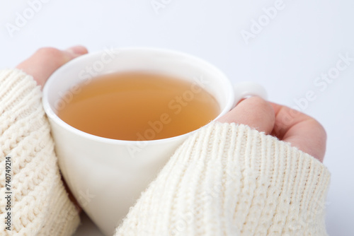 cup of tea with a knitted sweater on a female hand.