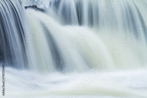 Winter landscape of the Rabbit River Cascade framed by ice and captured with motion blur  Michigan  USA