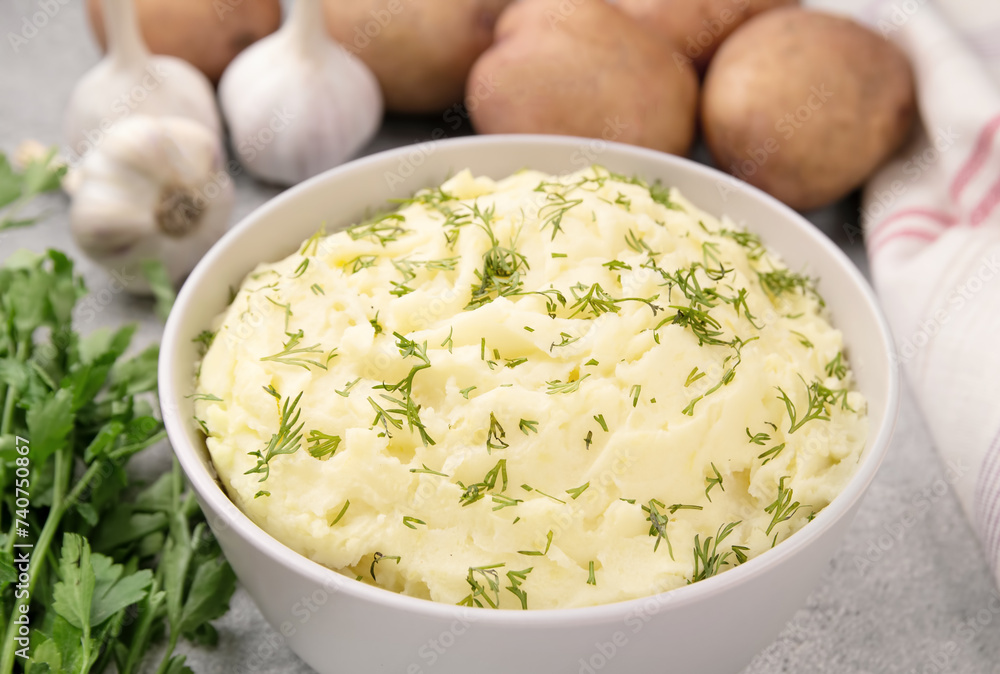 Bowl of tasty mashed potato, parsley, and pepper on grey marble table Bowl of tasty mashed potato, parsley, and pepper on grey marble table