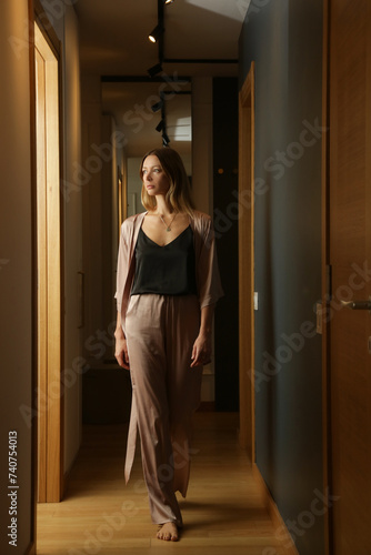 Portrait of young woman in elegant silk loungewear in the apartment