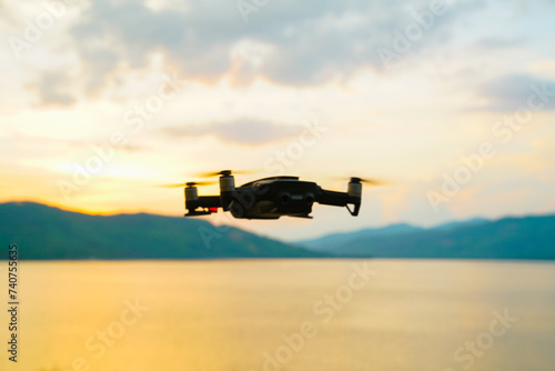 Silhouette drone flying over lake sunset