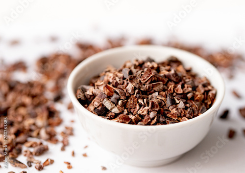 Organic Cacao Nibs in a White Ceramic Bowl. View from Above. Vegan Chocolate Concept.