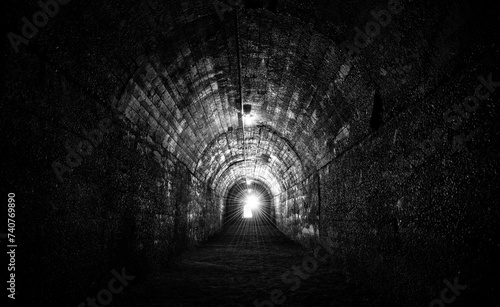 Historic bunker tunnel from world war 2 built with reinforced concrete now is a scary lost place in the dark with stalactites, old light bulbs, wet walls, spooky atmosphere. Black and white vintage.