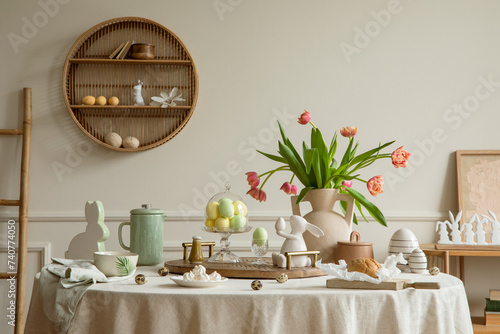 Photography Creative composition of easter dining room interior with round table, vase with tulips, colorful eggs, pitcher, wooden trace, bread, hare sculpture and personal accessories