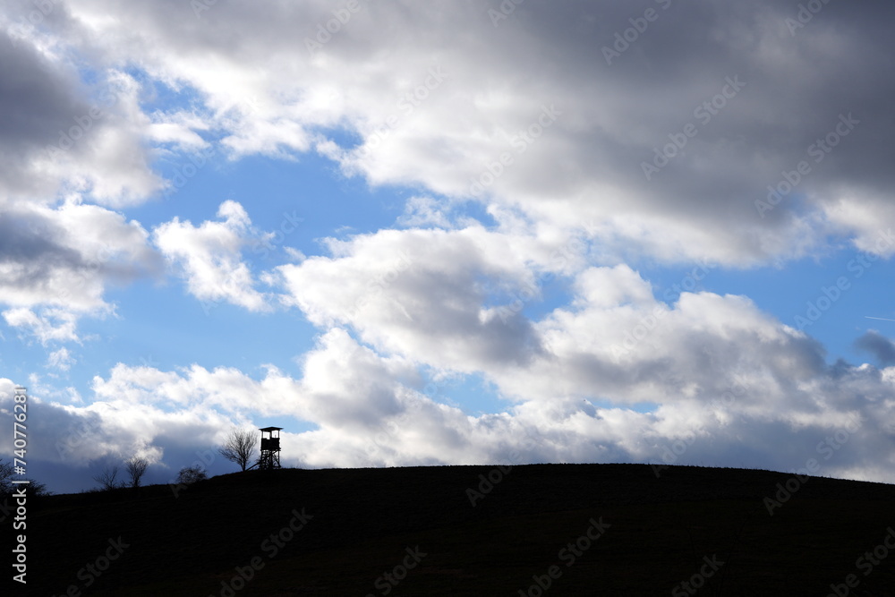 Wolkenbild mit  schwarzer Silhouette von Feld, Anstand, Ansitz zur Jagd, Wolken, Himmel, blau, weiß, Harz, Deutschland, Europa