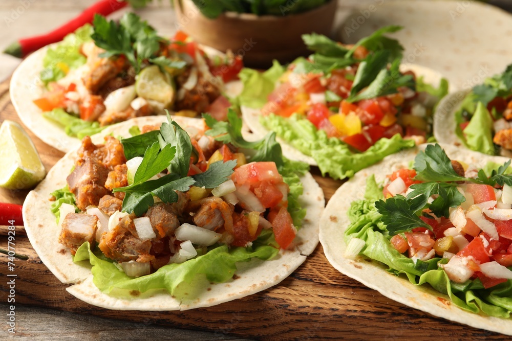 Delicious tacos with vegetables and meat on table, closeup