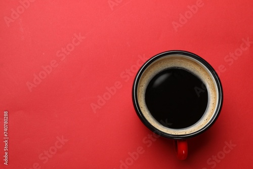 Fresh coffee in cup on red background, top view. Space for text