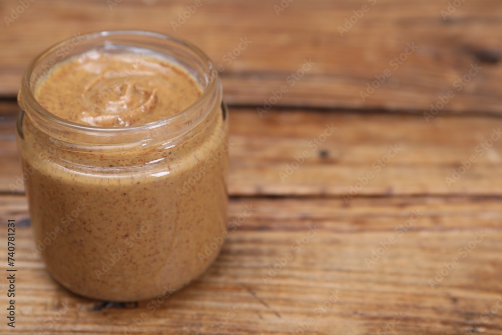 Tasty nut paste in jar on wooden table, closeup. Space for text Tasty nut paste in jar on wooden table, closeup. Space for text