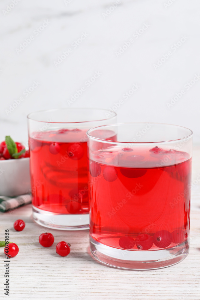 Tasty cranberry juice in glasses and fresh berries on white wooden table Tasty cranberry juice in glasses and fresh berries on white wooden table