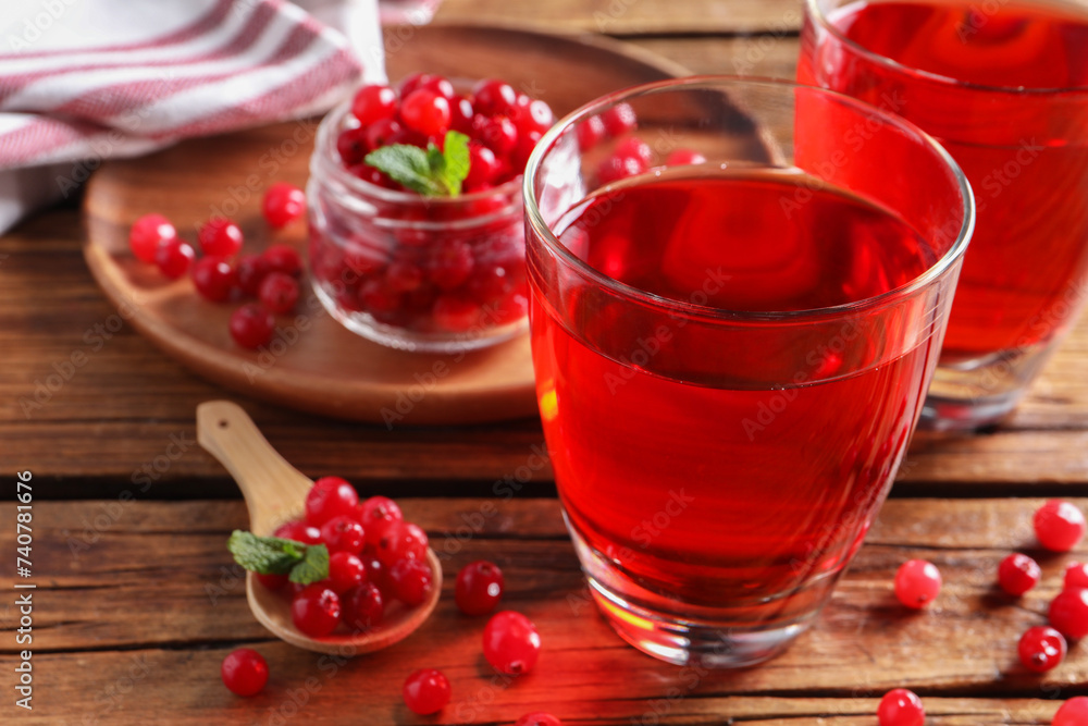 Tasty cranberry juice in glasses and fresh berries on wooden table, closeup Tasty cranberry juice in glasses and fresh berries on wooden table, closeup