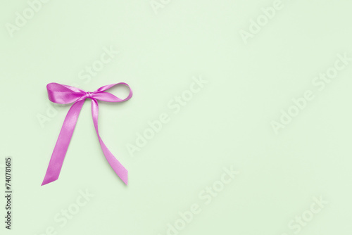 Purple bow on green background. Top view, copy space