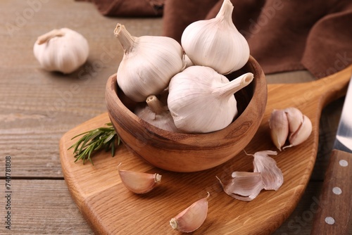 Fresh garlic and knife on wooden table, closeup. Space for text