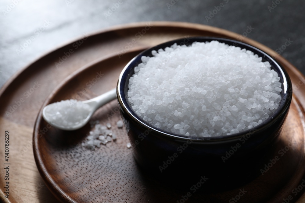Organic white salt in bowl and spoon on table, closeup