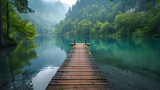 A serene wooden dock stretches into a tranquil green lake surrounded by lush forest in a misty morning.