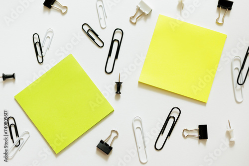 two sticky notes and paperclips over white