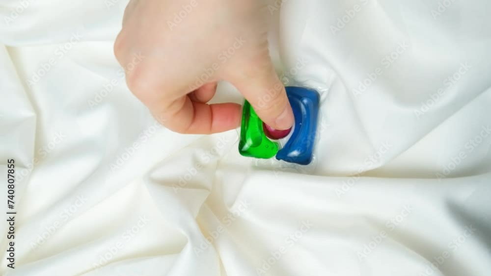 Housewife taking laundry capsule from satin fabric background, vertical shoot Housewife taking laundry capsule from satin fabric background, vertical shoot