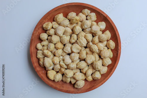 Dried Indonesian Candlenuts, or Kemiri, the seed of Aleurites moluccanus . On a wooden plate. Flat lay or top view