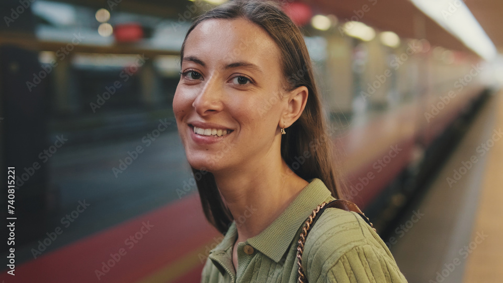 Close-up of a young laughing woman looking at the camera at a train station