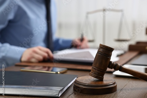 Lawyer working with documents at wooden table, focus on gavel