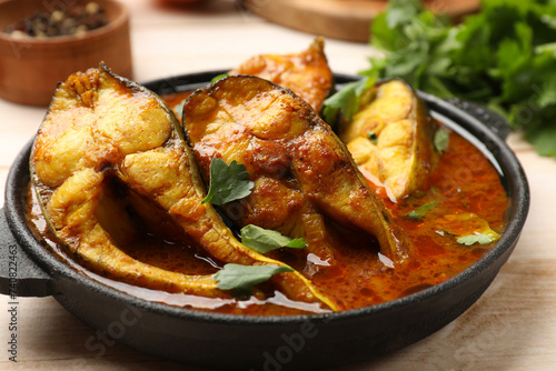 Tasty fish curry on white wooden table, closeup. Indian cuisine