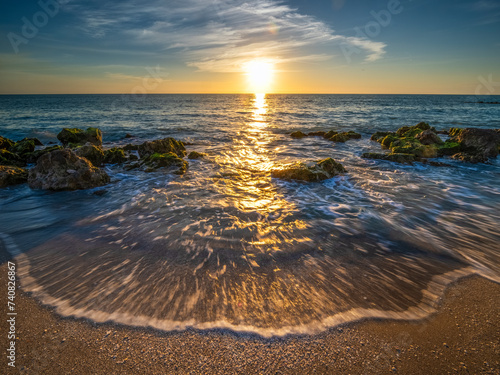 Small waves washing up on rocky beach of the Gulf of Mexico at Caspersen Beach at sunset in Venice Florida USA