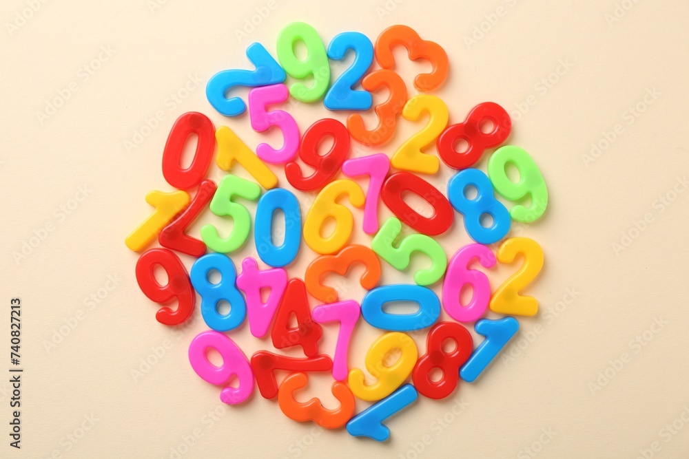 Colorful numbers on beige background, top view