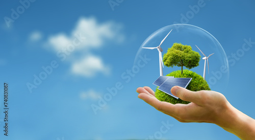 Business hand holds green globe with tree, wind turbine and solar powered for ESG, CO2 and Net Zero concept for sustainable corporate environmental development. Save the environment. 