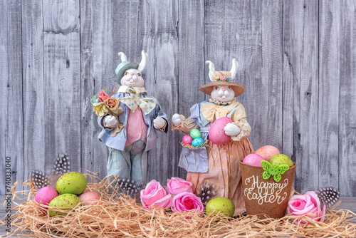 Easter decorative bunnies are decorated with colored eggs. Easter decoration. Happy Easter text. Grey background. photo