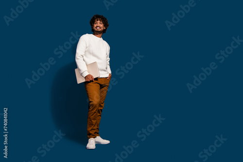 Full length photo of cool cheerful man wear white sweater working modern gadget empty space isolated dark blue color background