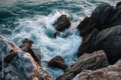 Waves crash forcefully against the rugged rocks of a shoreline, creating a dramatic and dynamic spectacle, Elevated capture of the seaâ€™s restive dance around the edgy rocks, AI Generated