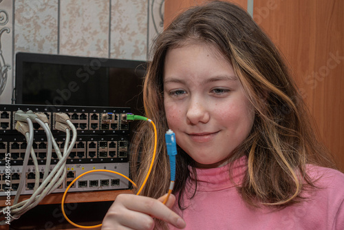 The girl is holding an internet cable in her hands. A child learns to set up a local computer network.