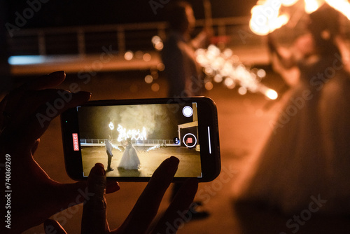 Fire show. The girl takes a video on her phone. Burning hearts.