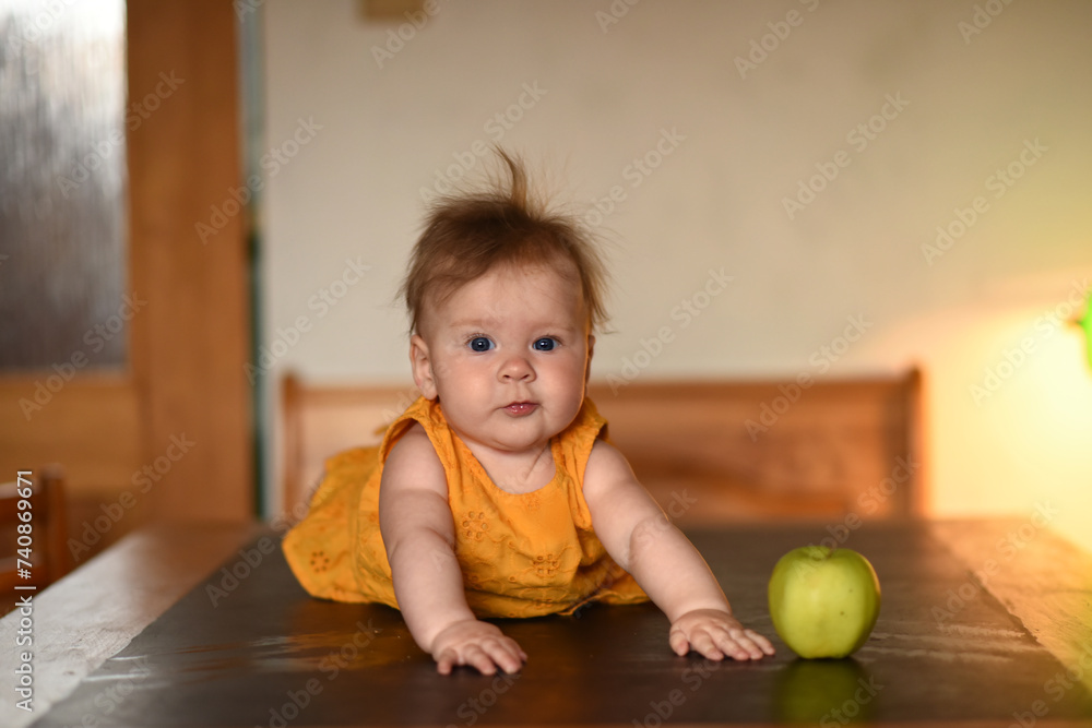 Small child with a green apple. The baby is lying on his stomach. A 4 month old baby lies on his stomach and holds his head. Small child with a green apple. The baby is lying on his stomach. A 4 month old baby lies on his stomach and holds his head.