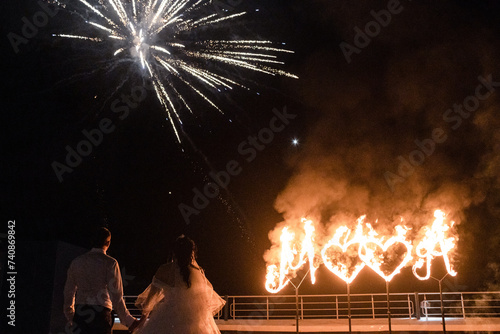 Fire show. The newlyweds hold hands against the background of fiery hearts and fireworks. Wedding, show program.