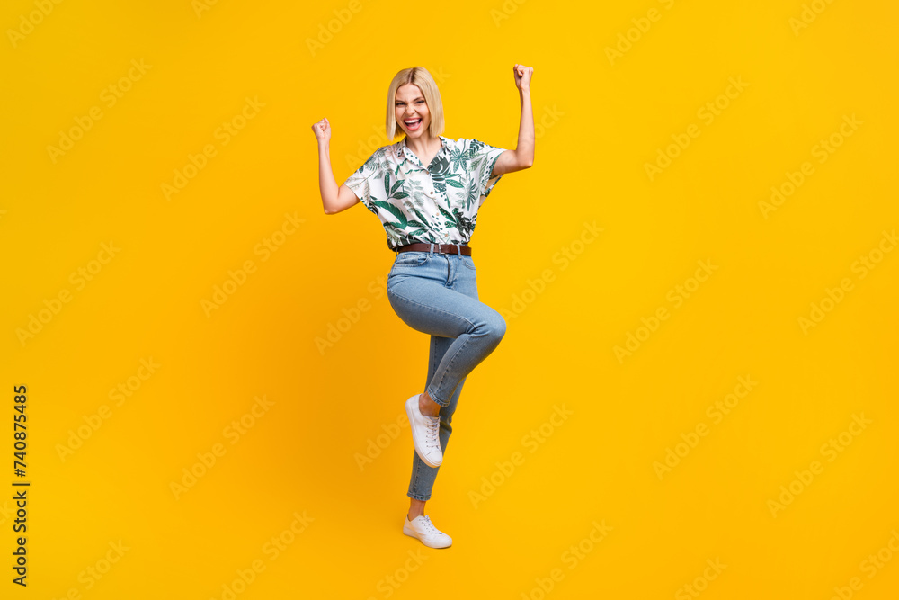 Full length photo of ecstatic girl dressed print blouse jeans shout yeah clenching fists win gambling isolated on yellow color background Full length photo of ecstatic girl dressed print blouse jeans shout yeah clenching fists win gambling isolated on yellow color background
