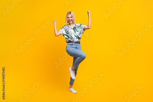 Full length photo of ecstatic girl dressed print blouse jeans shout yeah clenching fists win gambling isolated on yellow color background