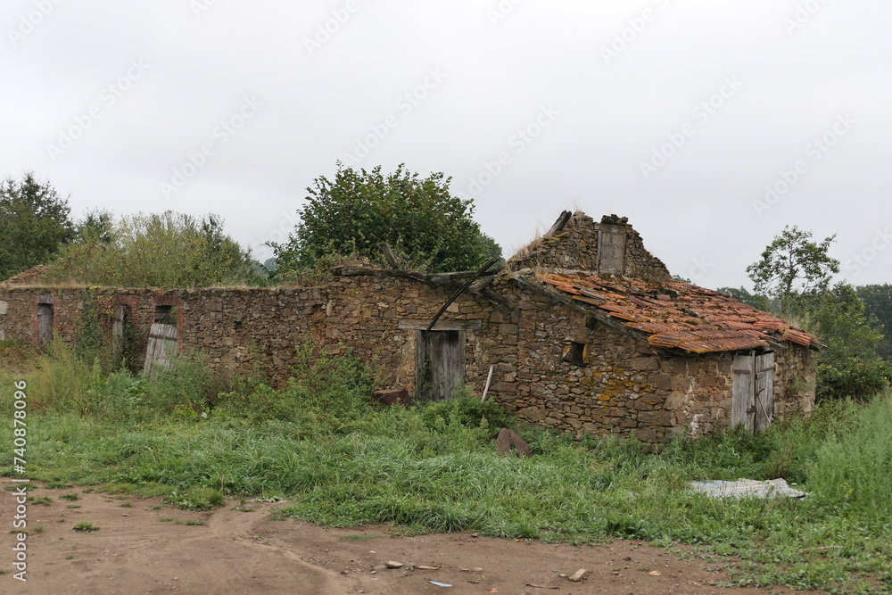 An overgrown old house nestled in a French rural area, its weathered façade and surrounding vegetation telling tales of time gone by.