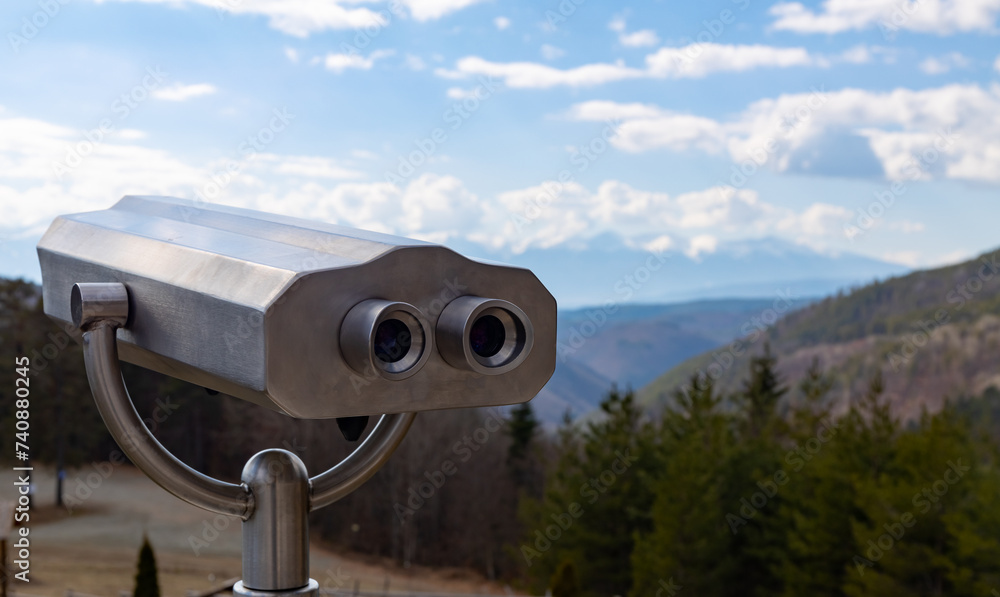 Shiny metal binoculars in the forest to observe the mountain peaks and the beautiful view.
