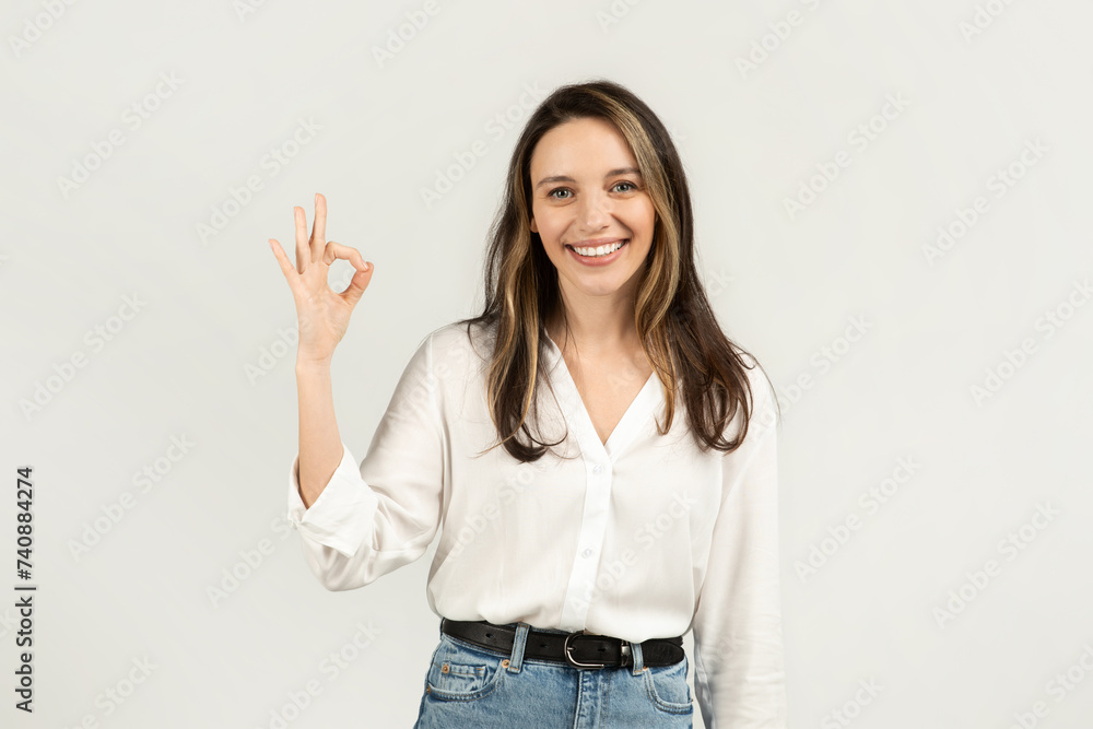 A smiling young woman with brunette hair, making an 'OK' sign with her fingers A smiling young woman with brunette hair, making an 'OK' sign with her fingers