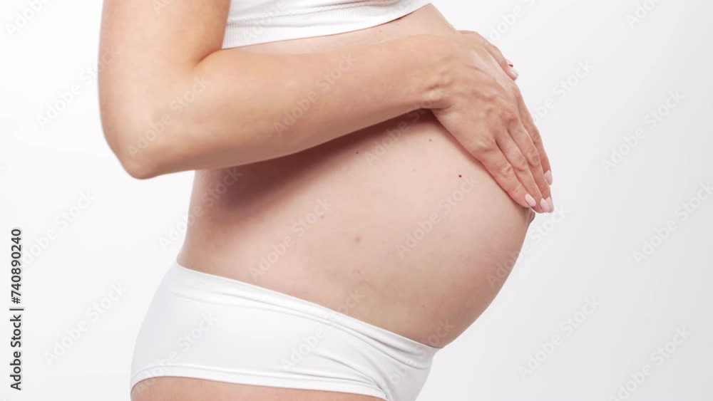 Young, happy and healthy pregnant woman in front of white background. Studio video. Baby expectation, pregnancy and motherhood. Young, happy and healthy pregnant woman in front of white background. Studio video. Baby expectation, pregnancy and motherhood.