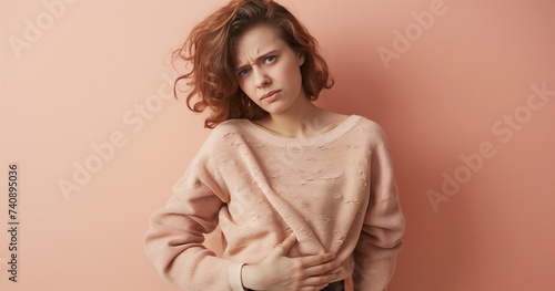 Worried young woman with painful PMS cramps, bloated and stomachache, pink background