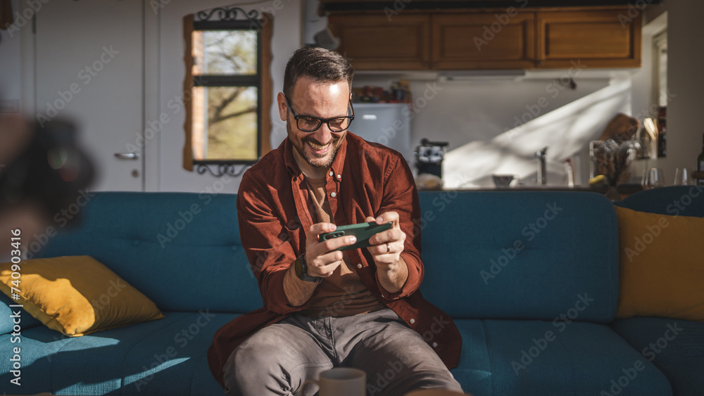 Obraz premium caucasian man sit at home play video games on smartphone mobile phone