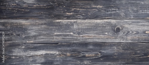 A close-up image showing a rectangular wooden table with a gray wood grain texture on its surface. The patterns of the hardwood plank create a unique flooring feature. photo