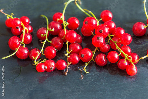 Close up for heap of red currant berries on a black stone background