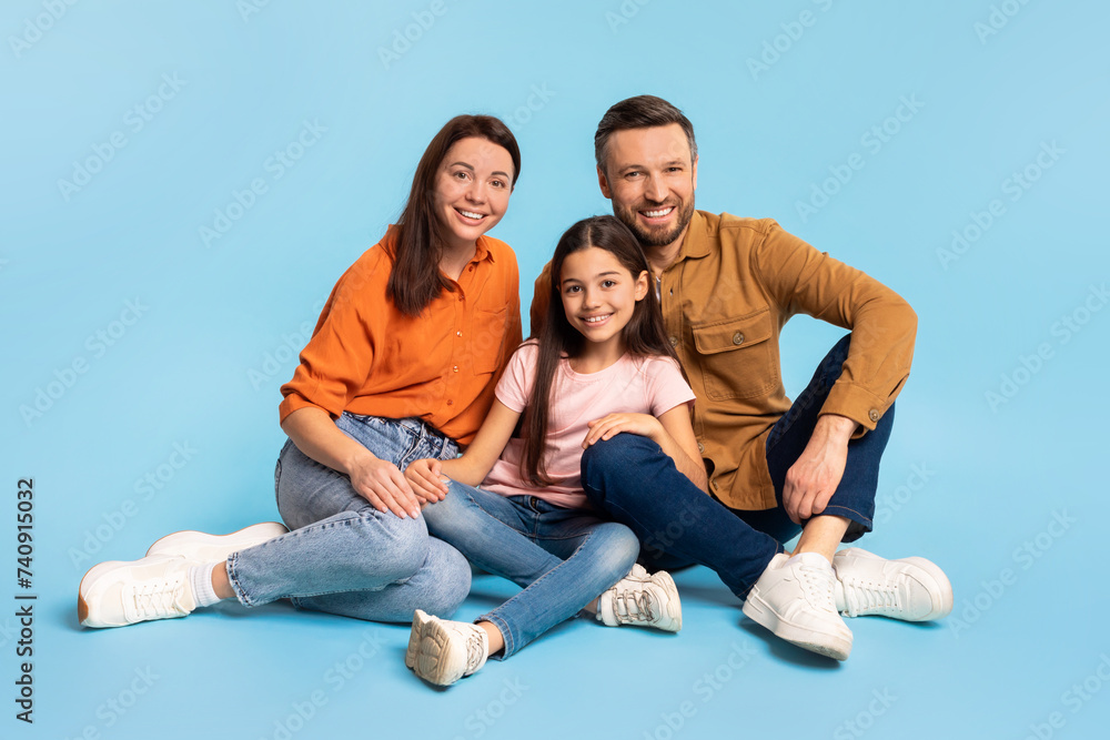 Family of parents and daughter shares hug sitting on floor Family of parents and daughter shares hug sitting on floor